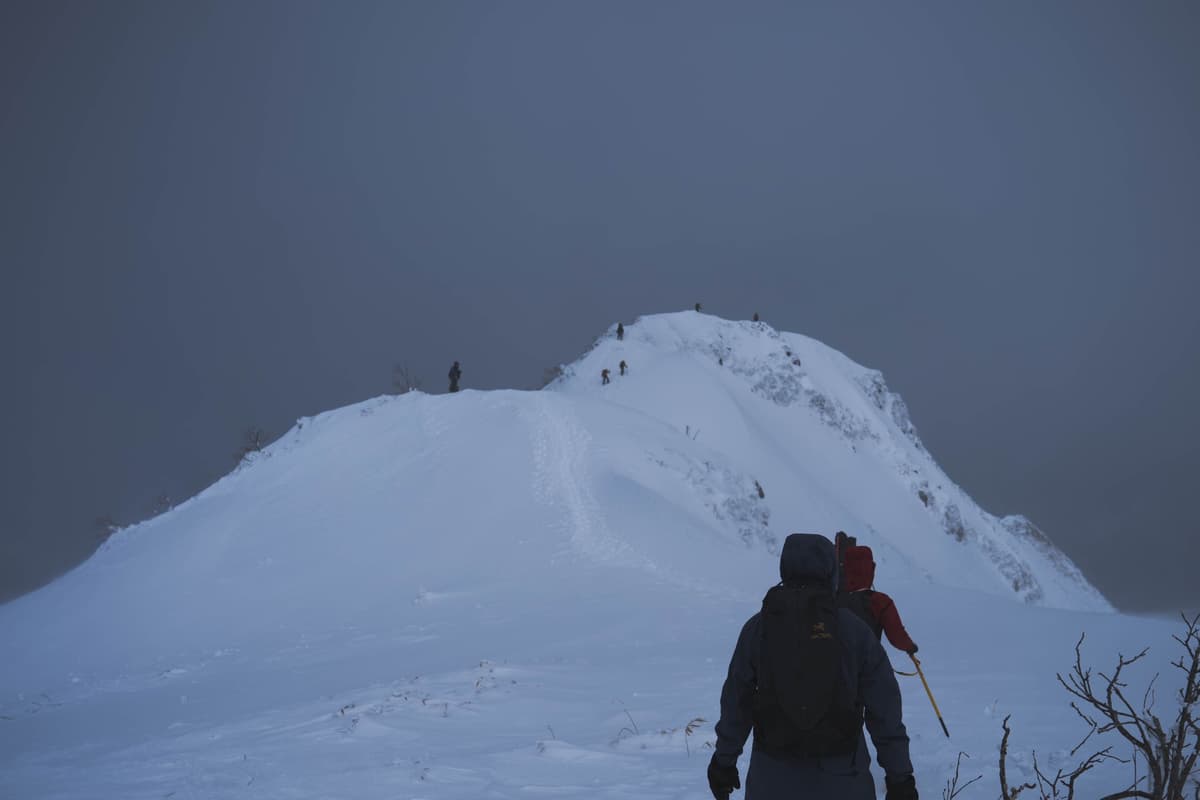 薄暗い雪稜を登る人影