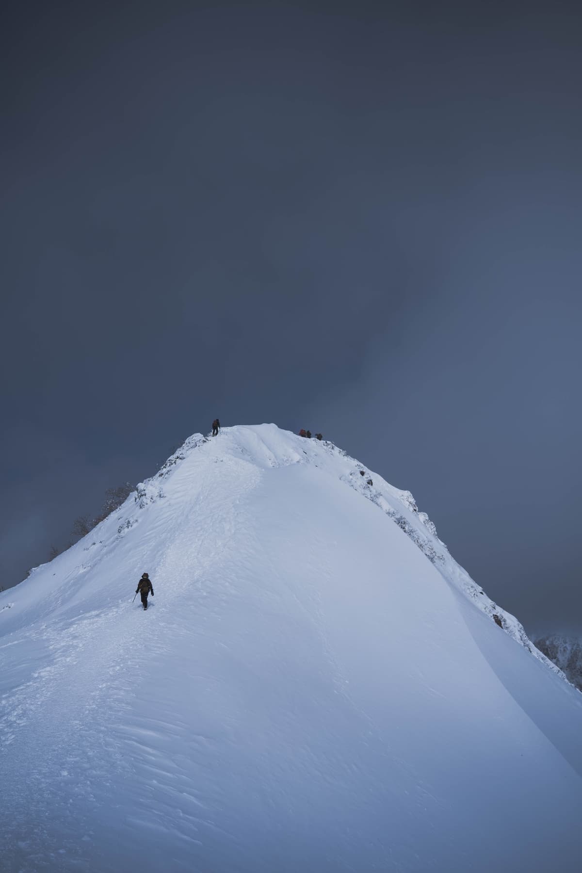 暗雲の下を進む登山者